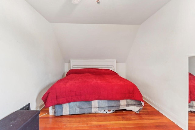 bedroom featuring baseboards, lofted ceiling, and wood finished floors