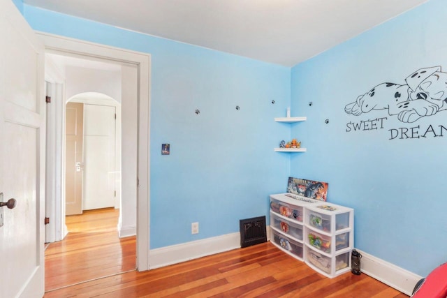 interior space with wood finished floors, arched walkways, and baseboards