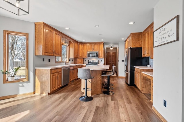 kitchen featuring a breakfast bar, light wood-type flooring, a wealth of natural light, and stainless steel appliances