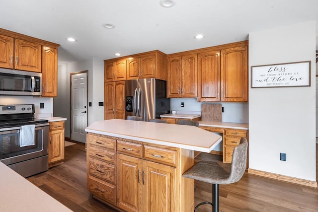 kitchen featuring brown cabinets, dark wood-type flooring, appliances with stainless steel finishes, and light countertops