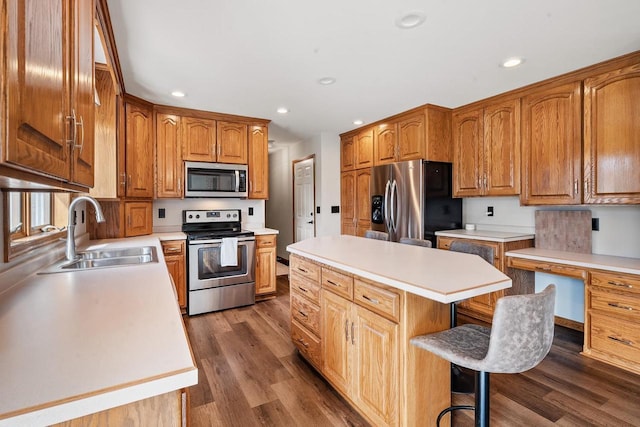 kitchen featuring a kitchen island, dark wood-style flooring, a sink, light countertops, and appliances with stainless steel finishes