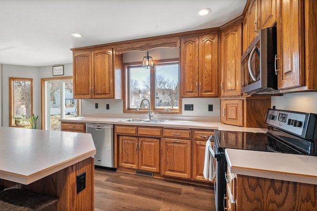 kitchen with a sink, a healthy amount of sunlight, brown cabinetry, and stainless steel appliances