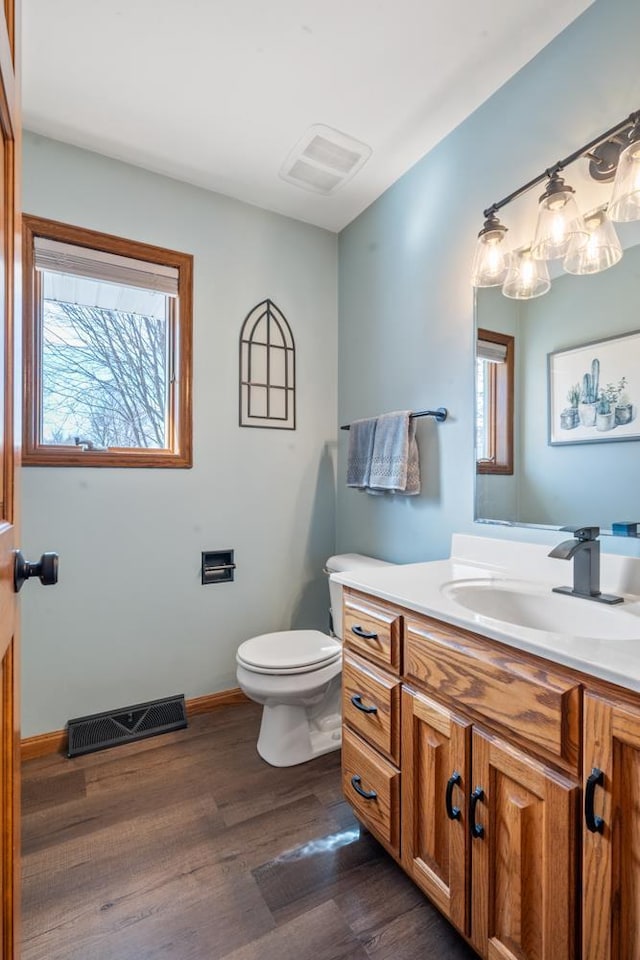 bathroom with vanity, toilet, wood finished floors, and visible vents