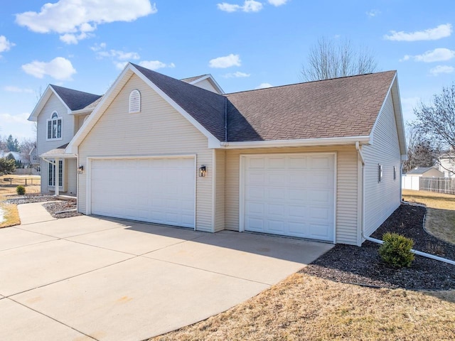 view of front of home featuring driveway, a garage, and roof with shingles