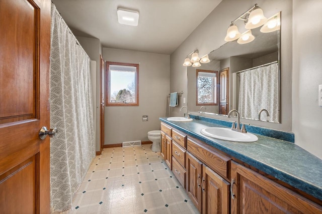 bathroom with a sink, visible vents, double vanity, and tile patterned floors