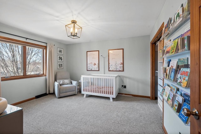 bedroom with a crib, carpet flooring, baseboards, and a chandelier