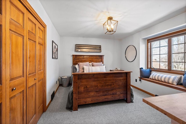 carpeted bedroom featuring a notable chandelier and baseboards