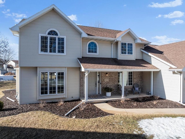 view of front of home featuring brick siding and roof with shingles