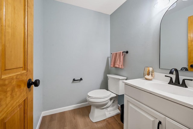 bathroom featuring vanity, toilet, wood finished floors, and baseboards