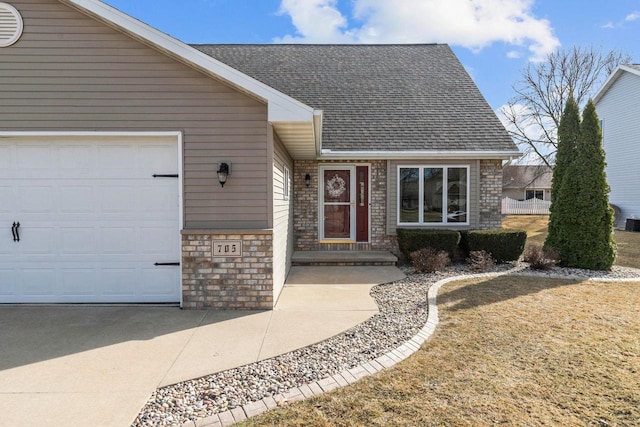 ranch-style house with brick siding, a shingled roof, concrete driveway, stone siding, and an attached garage