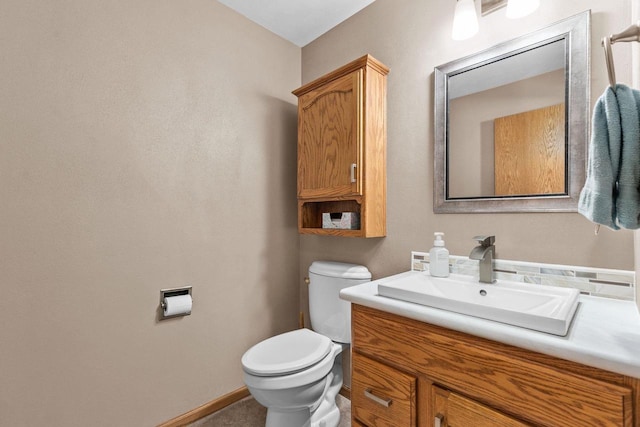 bathroom with baseboards, toilet, and vanity