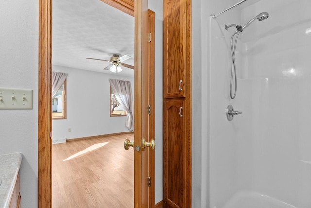 full bath featuring a walk in shower, a ceiling fan, and wood finished floors