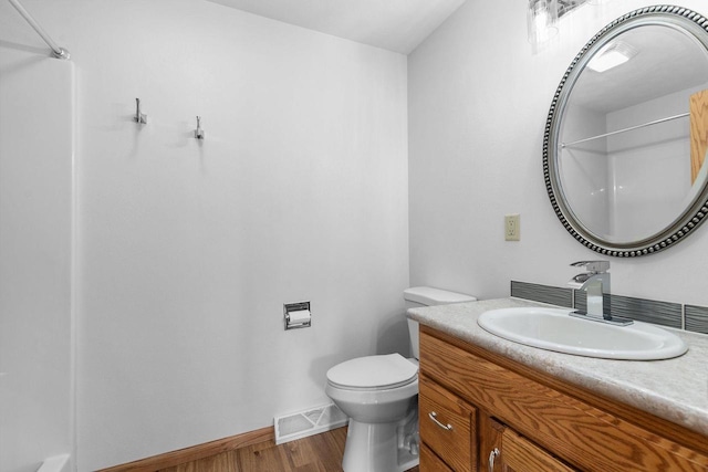 bathroom featuring vanity, wood finished floors, visible vents, baseboards, and toilet