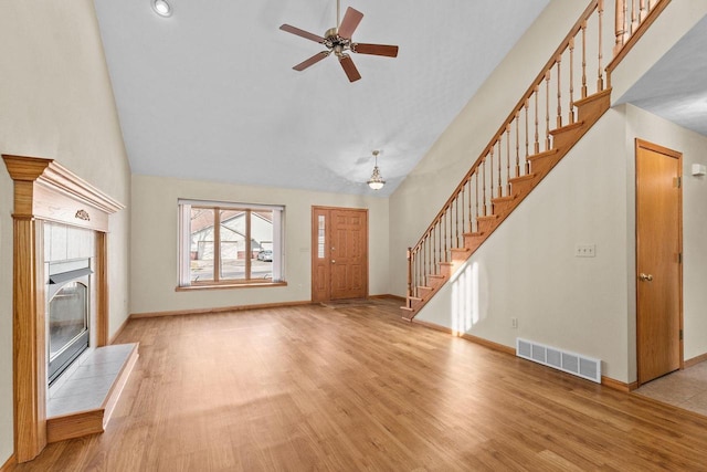 unfurnished living room with wood finished floors, stairway, a fireplace, and visible vents