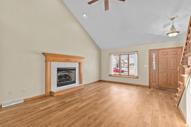 unfurnished living room with stairway, baseboards, visible vents, light wood-style flooring, and a tile fireplace