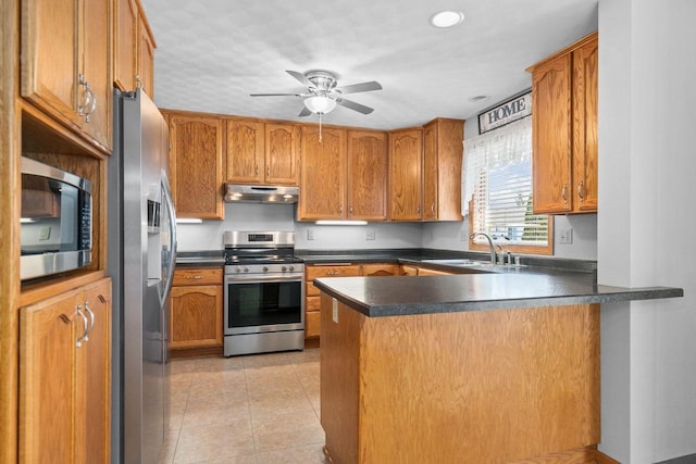 kitchen with under cabinet range hood, appliances with stainless steel finishes, a peninsula, light tile patterned flooring, and a sink