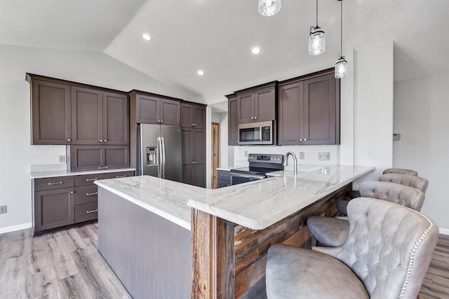 kitchen with light wood-style flooring, light stone counters, appliances with stainless steel finishes, a peninsula, and vaulted ceiling