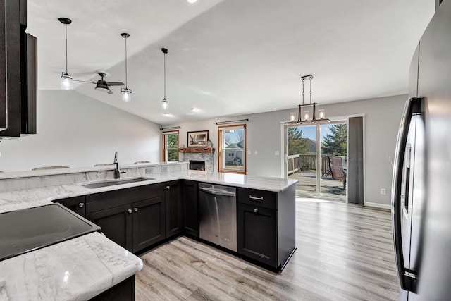 kitchen featuring light wood finished floors, appliances with stainless steel finishes, light stone countertops, and a sink