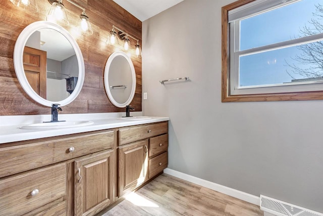 bathroom featuring double vanity, wood finished floors, visible vents, and a sink