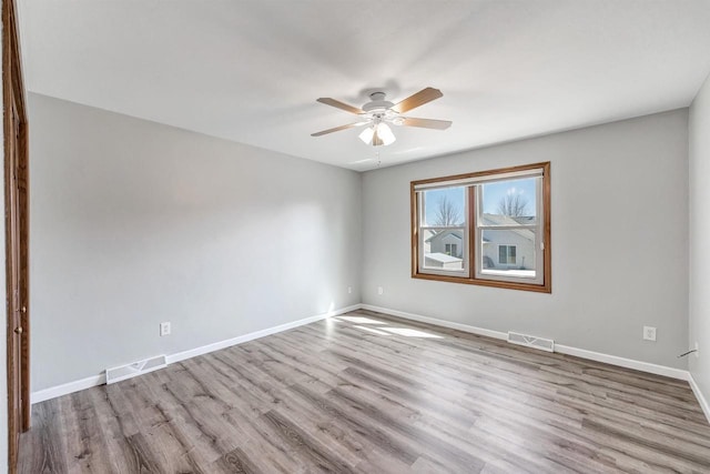 empty room with ceiling fan, visible vents, baseboards, and wood finished floors