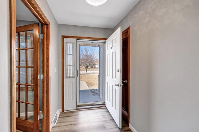 doorway to outside with wood finished floors, visible vents, and baseboards