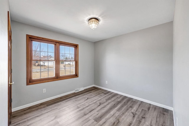 spare room featuring light wood-style flooring, visible vents, and baseboards