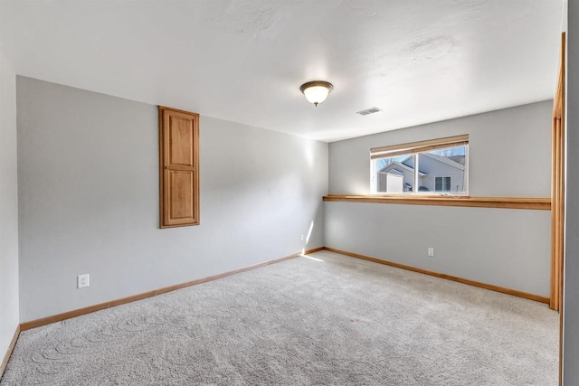 carpeted spare room featuring visible vents and baseboards