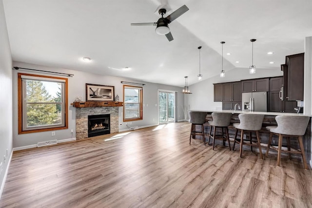 kitchen with visible vents, light wood-style flooring, a kitchen breakfast bar, stainless steel fridge with ice dispenser, and lofted ceiling