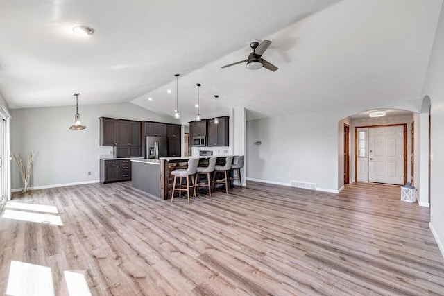 kitchen with a breakfast bar area, lofted ceiling, arched walkways, light countertops, and appliances with stainless steel finishes