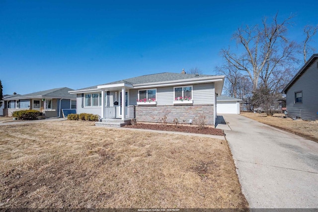 ranch-style home with stone siding, a front yard, a detached garage, and an outdoor structure