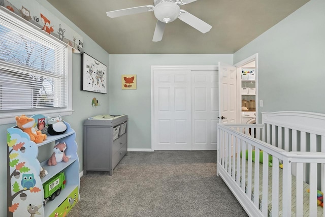 carpeted bedroom featuring a closet, baseboards, a ceiling fan, and a nursery area