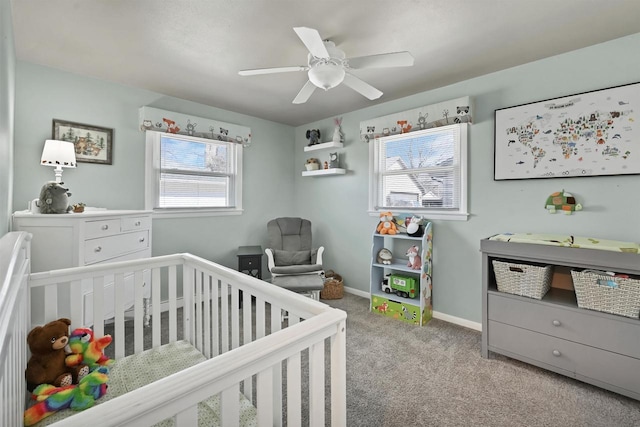 carpeted bedroom featuring ceiling fan, a crib, and baseboards