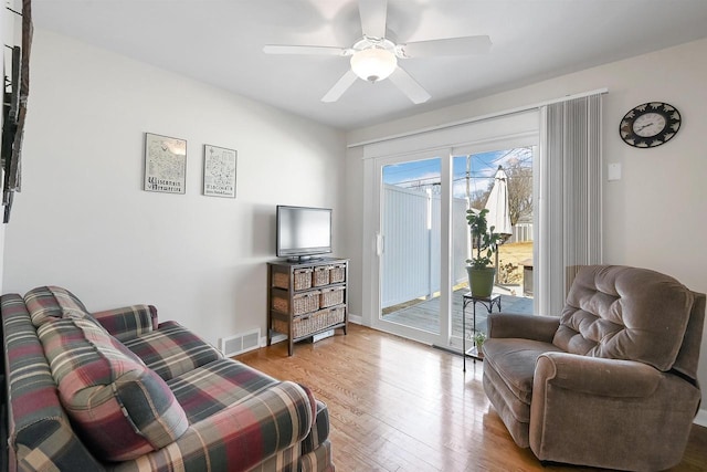 living room featuring visible vents, baseboards, light wood-style flooring, and a ceiling fan