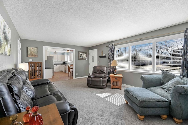 carpeted living room featuring ceiling fan, baseboards, and a textured ceiling