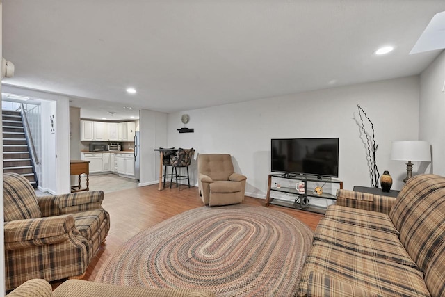 living room featuring recessed lighting, light wood-style flooring, stairs, and baseboards