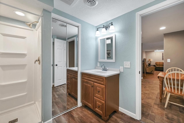 full bathroom with visible vents, vanity, ensuite bathroom, and a textured wall