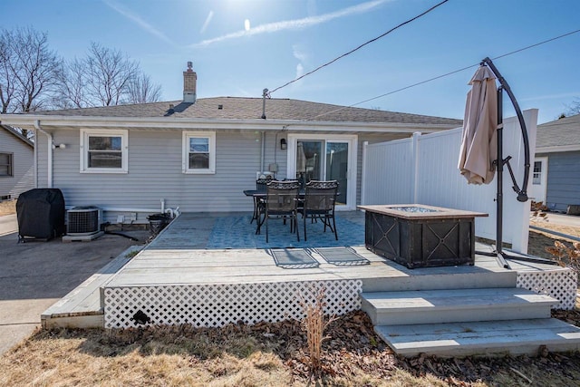 rear view of house with central AC, fence, an outdoor fire pit, a wooden deck, and a chimney