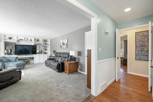 living room with wood finished floors, wainscoting, visible vents, and a textured ceiling