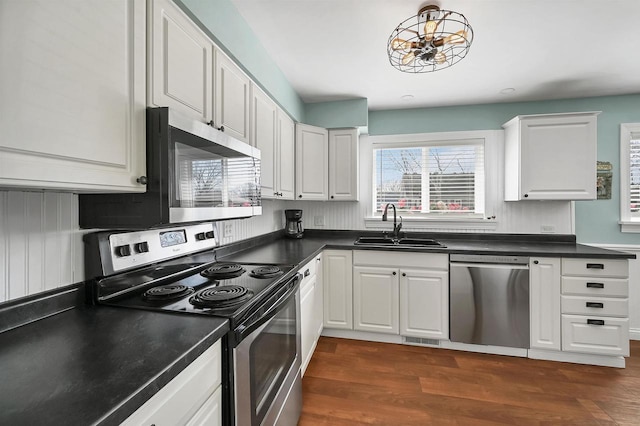 kitchen with dark countertops, dark wood finished floors, appliances with stainless steel finishes, and a sink