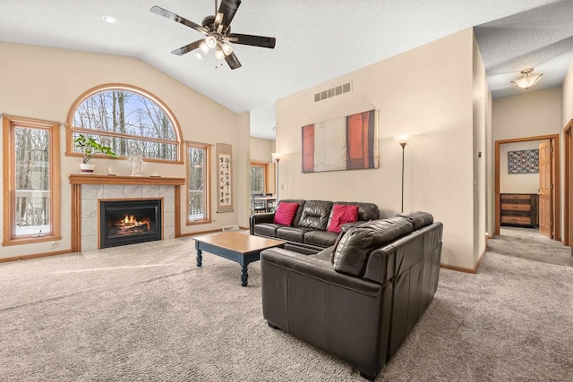 carpeted living room featuring baseboards, lofted ceiling, a fireplace, a textured ceiling, and a ceiling fan