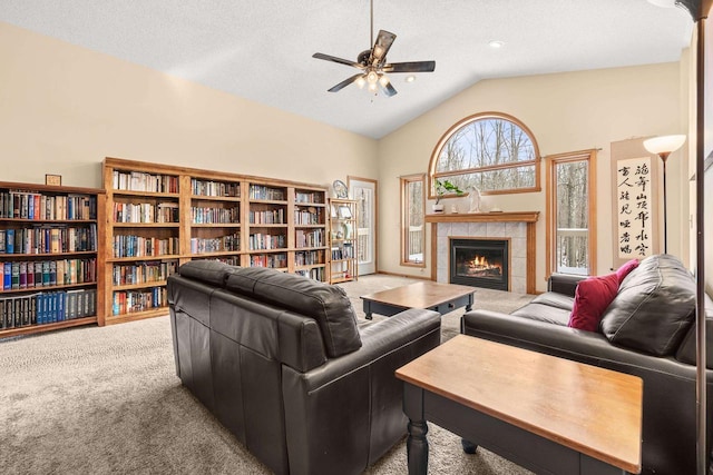 carpeted living area featuring a fireplace, a textured ceiling, a ceiling fan, and vaulted ceiling