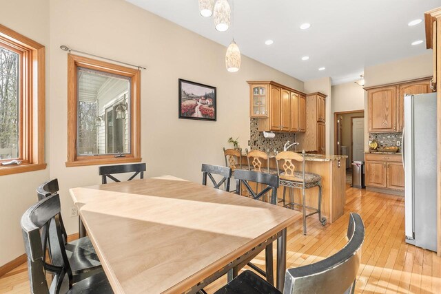 dining area with recessed lighting, baseboards, light wood-style floors, and vaulted ceiling