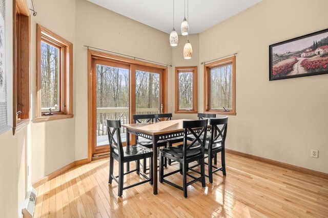 dining space with baseboards and light wood-style flooring