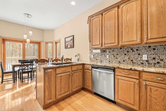 kitchen with light stone countertops, a peninsula, a sink, dishwasher, and backsplash