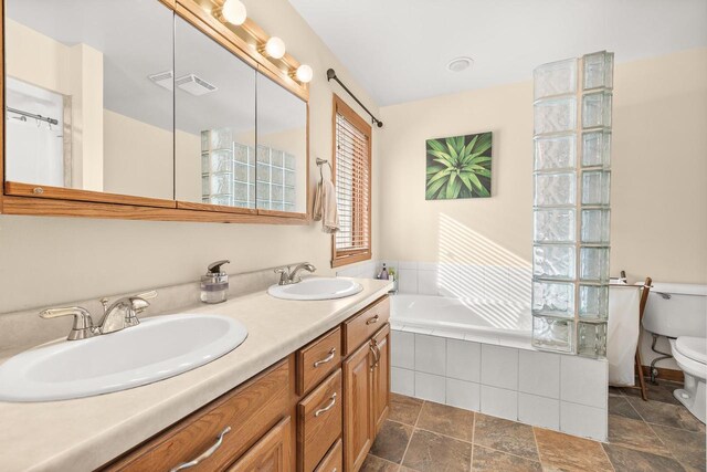 full bathroom featuring a sink, tiled tub, toilet, and double vanity