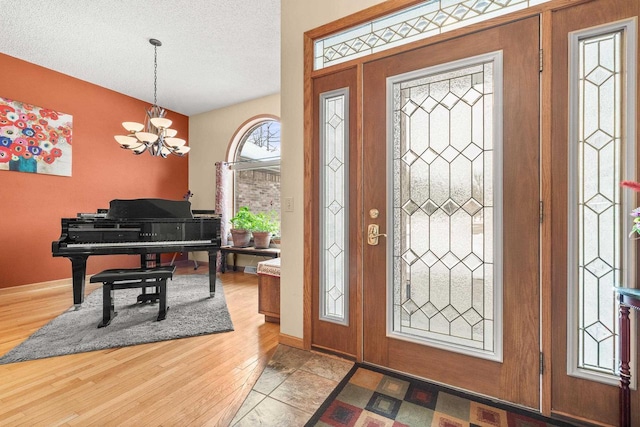 foyer featuring a notable chandelier, baseboards, a textured ceiling, and wood finished floors