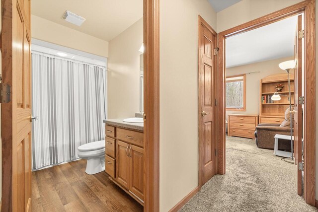 bathroom featuring vanity, toilet, wood finished floors, and visible vents