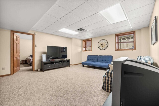 carpeted living area with baseboards, visible vents, and a drop ceiling