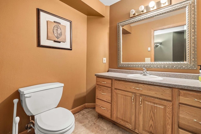 half bathroom with tile patterned floors, toilet, vanity, and baseboards