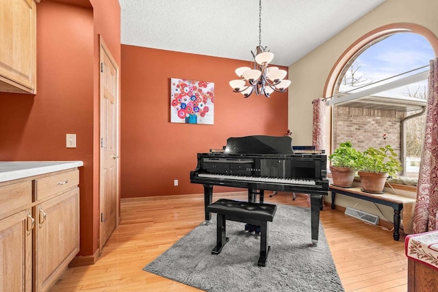 sitting room featuring light wood finished floors, visible vents, baseboards, a notable chandelier, and a textured ceiling